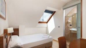 A hotel room with a bed, a desk, a chair, a bathroom with a shower, and a skylight. -  Hotel Longoria Plaza by Pandora Hoteles (Oviedo)
