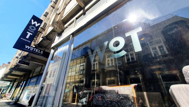 Un hôtel avec une grande enseigne sur laquelle on peut lire « WOTEL PORTO » et « WORLD OF TRAVELLERS ».