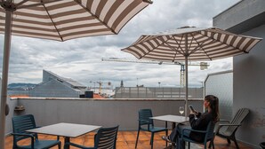 Una terraza con sombrillas a rayas, una mesa y sillas.