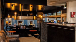 Un espace bar moderne doté d’un comptoir, de sièges et de luminaires suspendus.