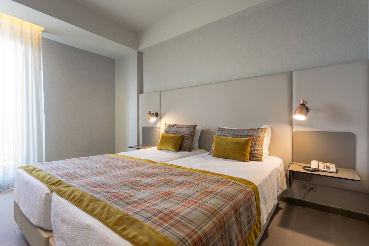 A hotel room with a double bed, two bedside tables, a telephone, and a lamp.