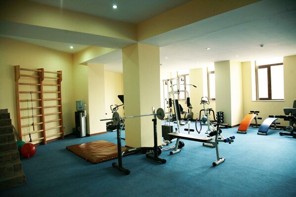 A gym with exercise equipment, a water dispenser, and a yoga mat.