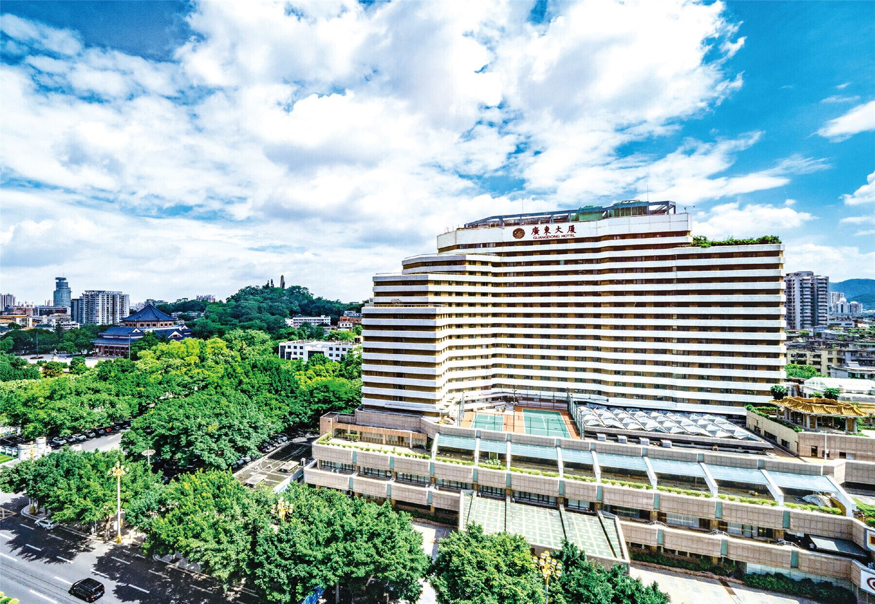 Un hotel de varios pisos con terraza en azotea plana y un cartel que indica que es el Hotel Guangdong.