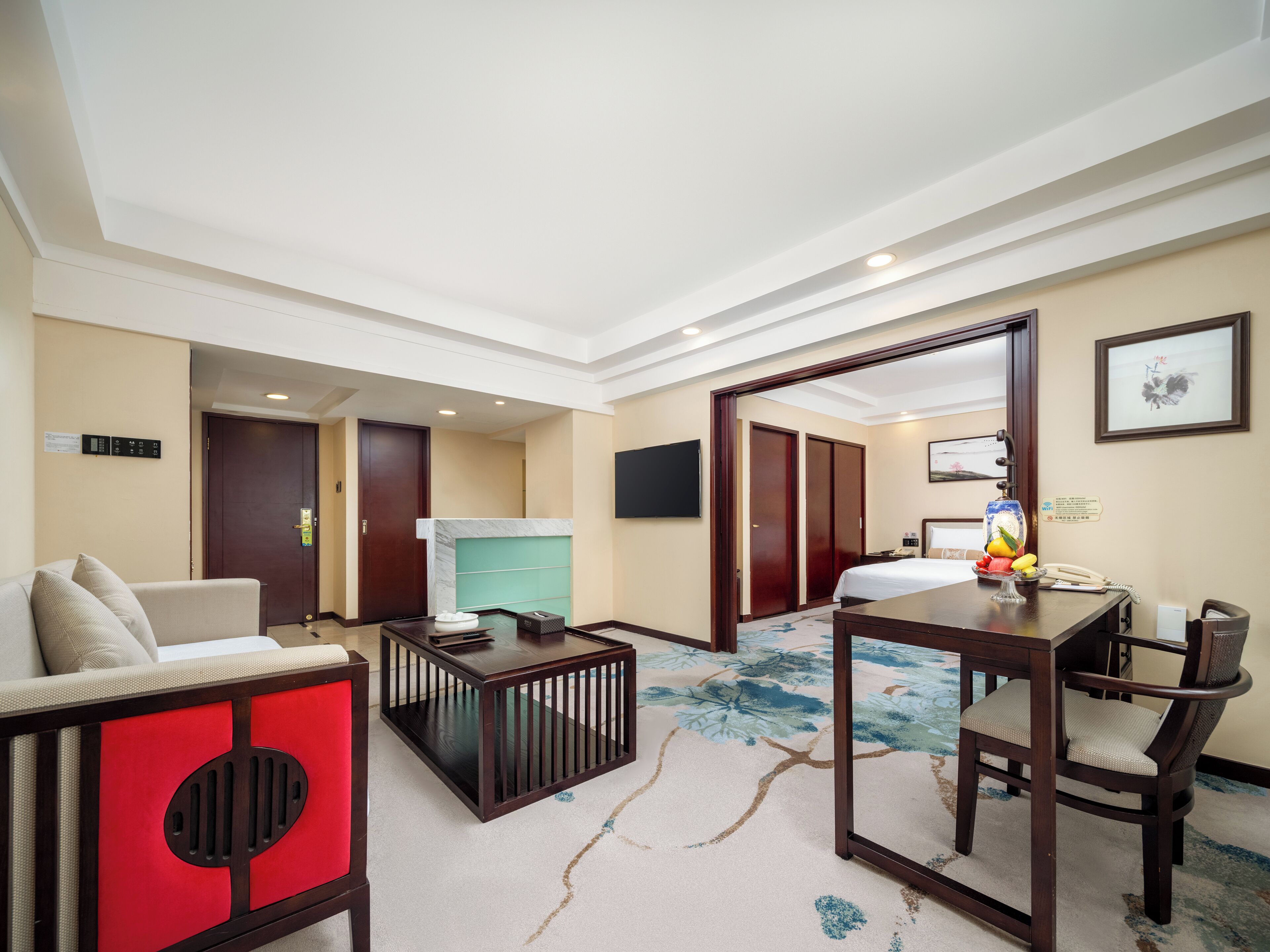 Habitación de hotel con sofá, una mesita, cama, televisión y baño con ducha e inodoro.