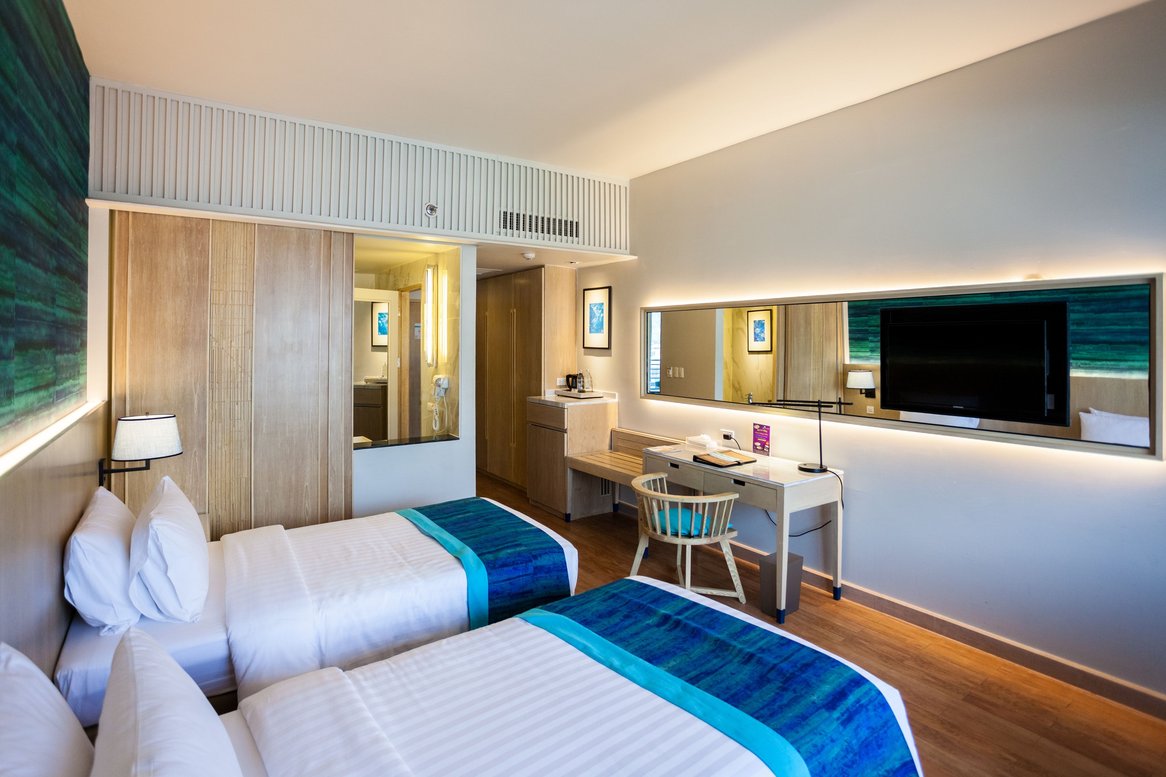 Une chambre d’hôtel avec deux lits, un bureau, une chaise, une télévision et une grande fenêtre.