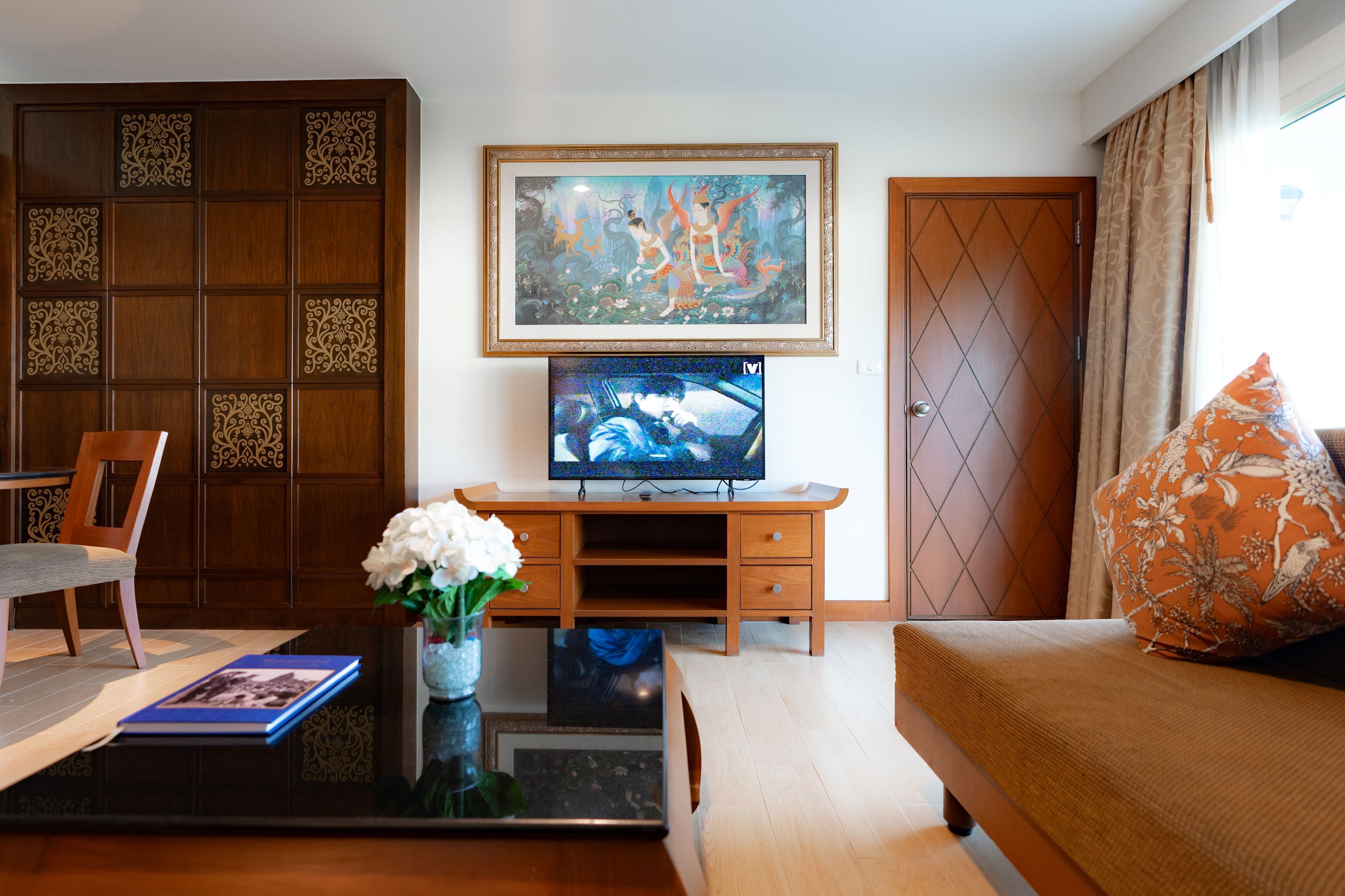 Un salon comprenant un meuble en bois, un téléviseur, un canapé et un tableau décoratif.