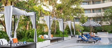 A poolside area with sun loungers and a canopy structure.