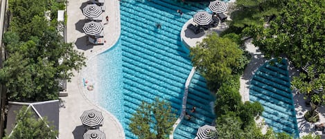 Relax by the pool surrounded by lush greenery and enjoy ample shade and relaxation spots.