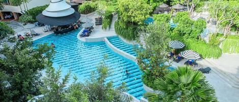 Zona de piscina en la azotea con varias pistas de natación, rodeada de palmeras y sillones de descanso.