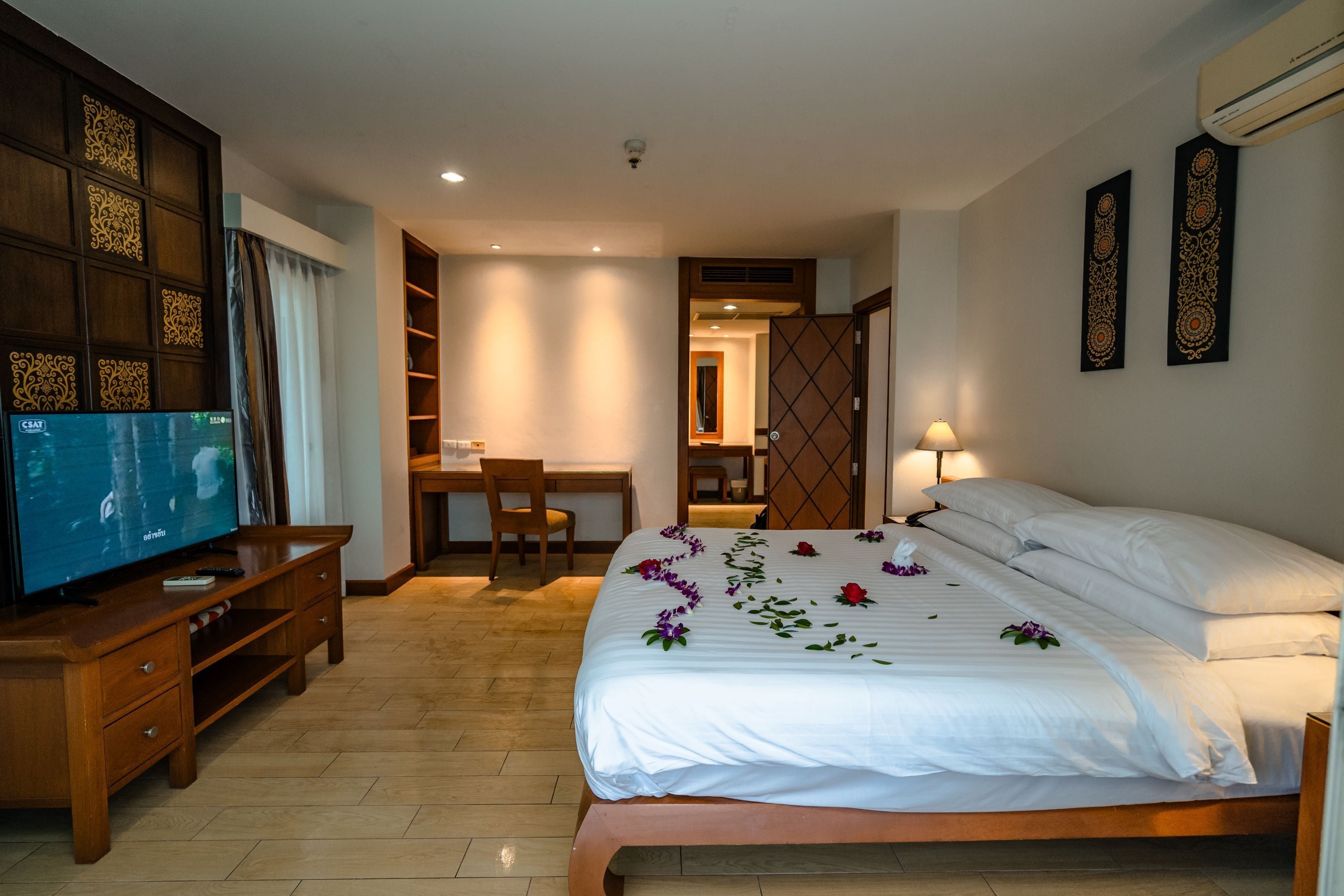 A hotel room with a bed, a TV, a desk, and a chair.