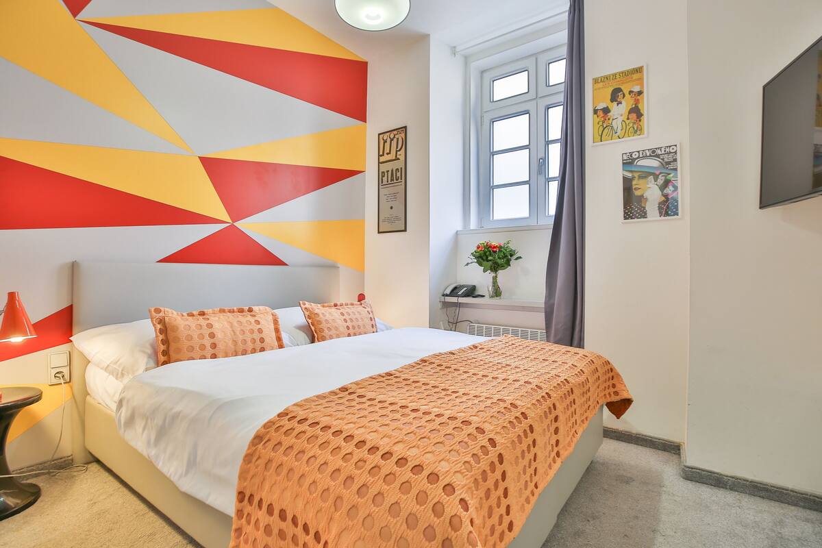 A hotel room with a bed, a desk, and a window.