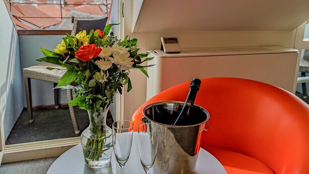 A balcony with a table, a vase of flowers, two glasses, and a champagne bottle. - LH Vintage Design Hotel Sax (Prague)