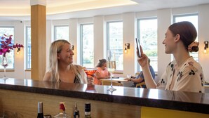 A bar area with a counter, a person holding a smartphone, and another person in the background. - Botel Racek (Prague)