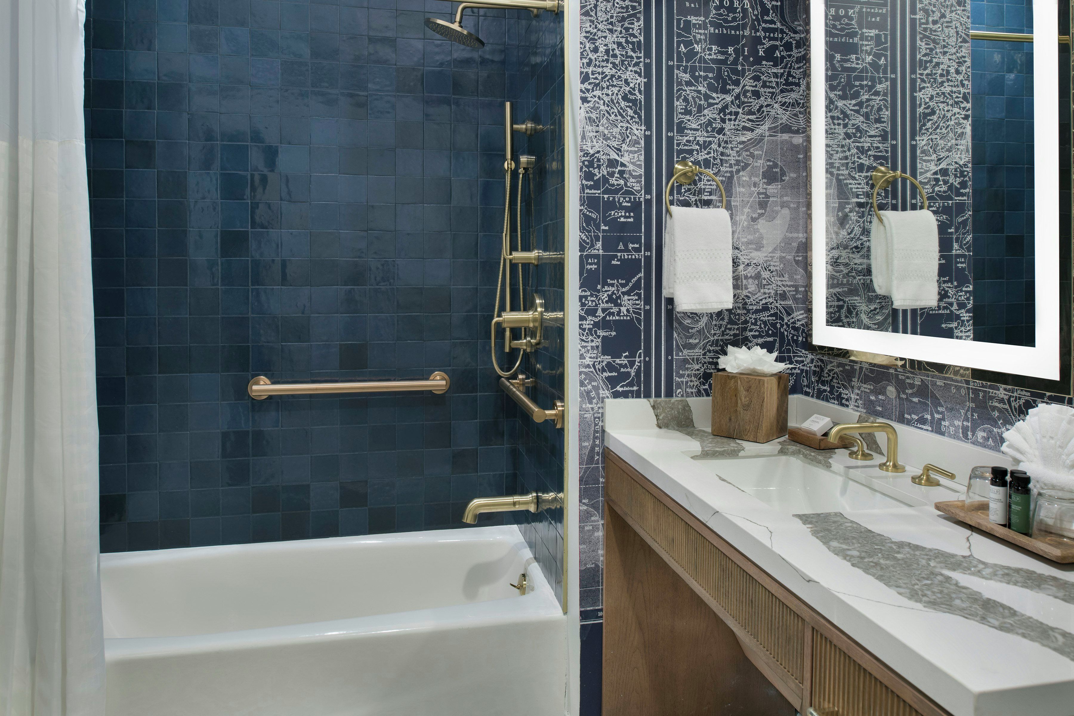 A bathroom with a bathtub, a shower with a rain showerhead, a vanity with a mirror, and a towel rack.