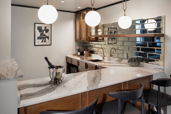 Una cocina moderna con encimeras de mármol, armarios de madera e iluminación colgante.