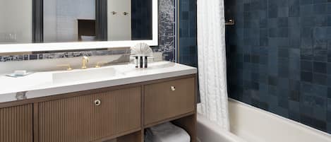 A modern bathroom with a large mirror, a white sink, and a bathtub.