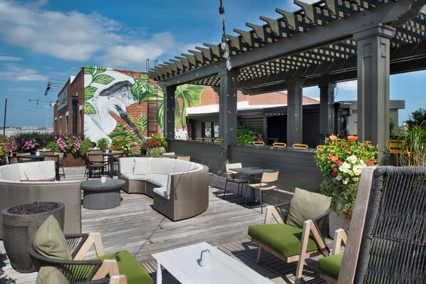An outdoor patio with wicker furniture, a mural, and a pergola.