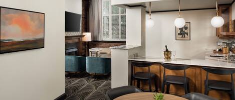 A modern kitchen with a central island, bar stools, and pendant lighting.