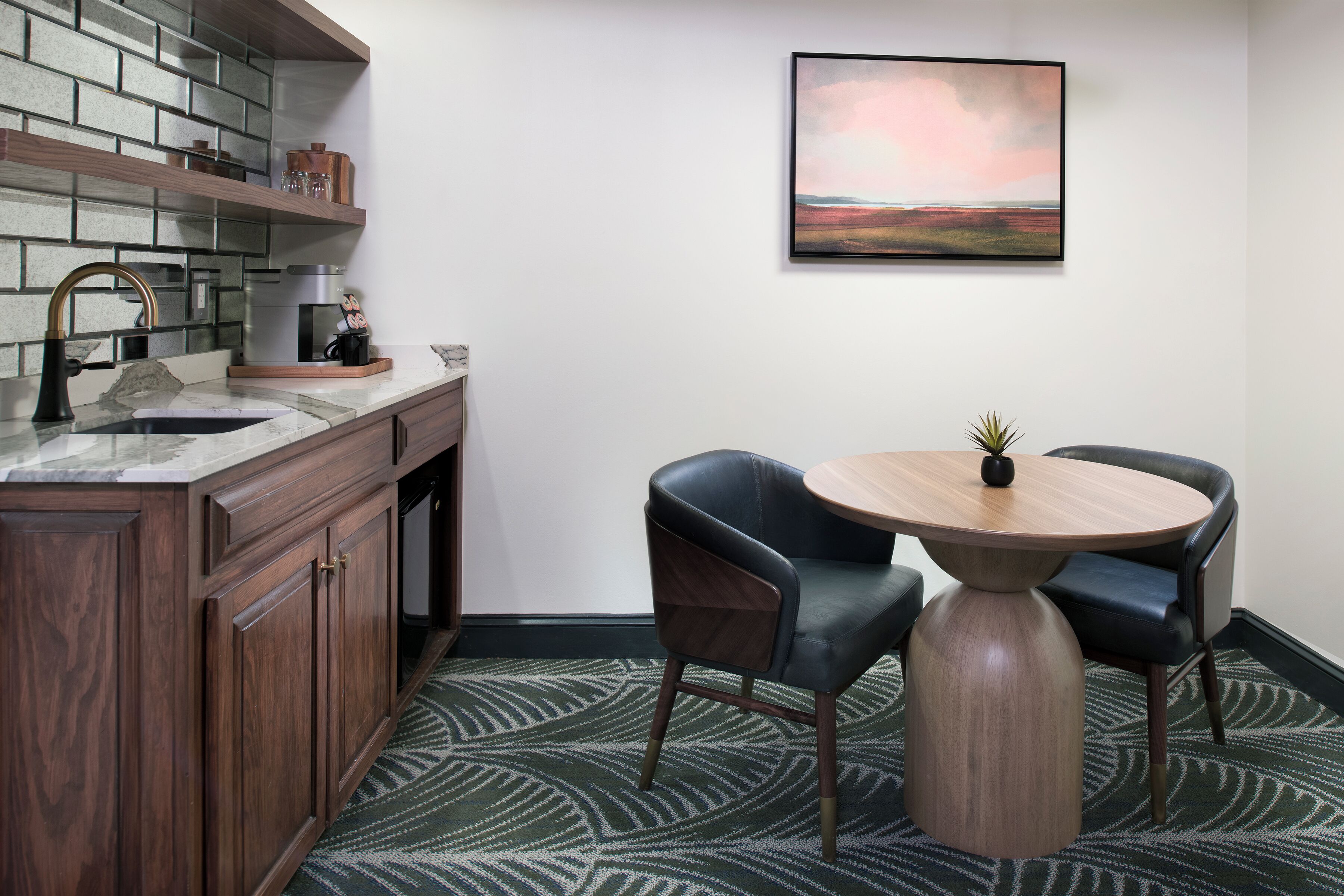 Cocina moderna con encimera de madera, un lavamanos y una zona de comedor con dos sillas y una mesa redonda.