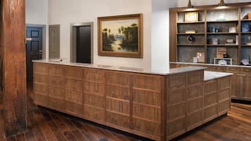 Kitchen features a large island with multiple drawers and a countertop, shelving unit, and a framed landscape painting.