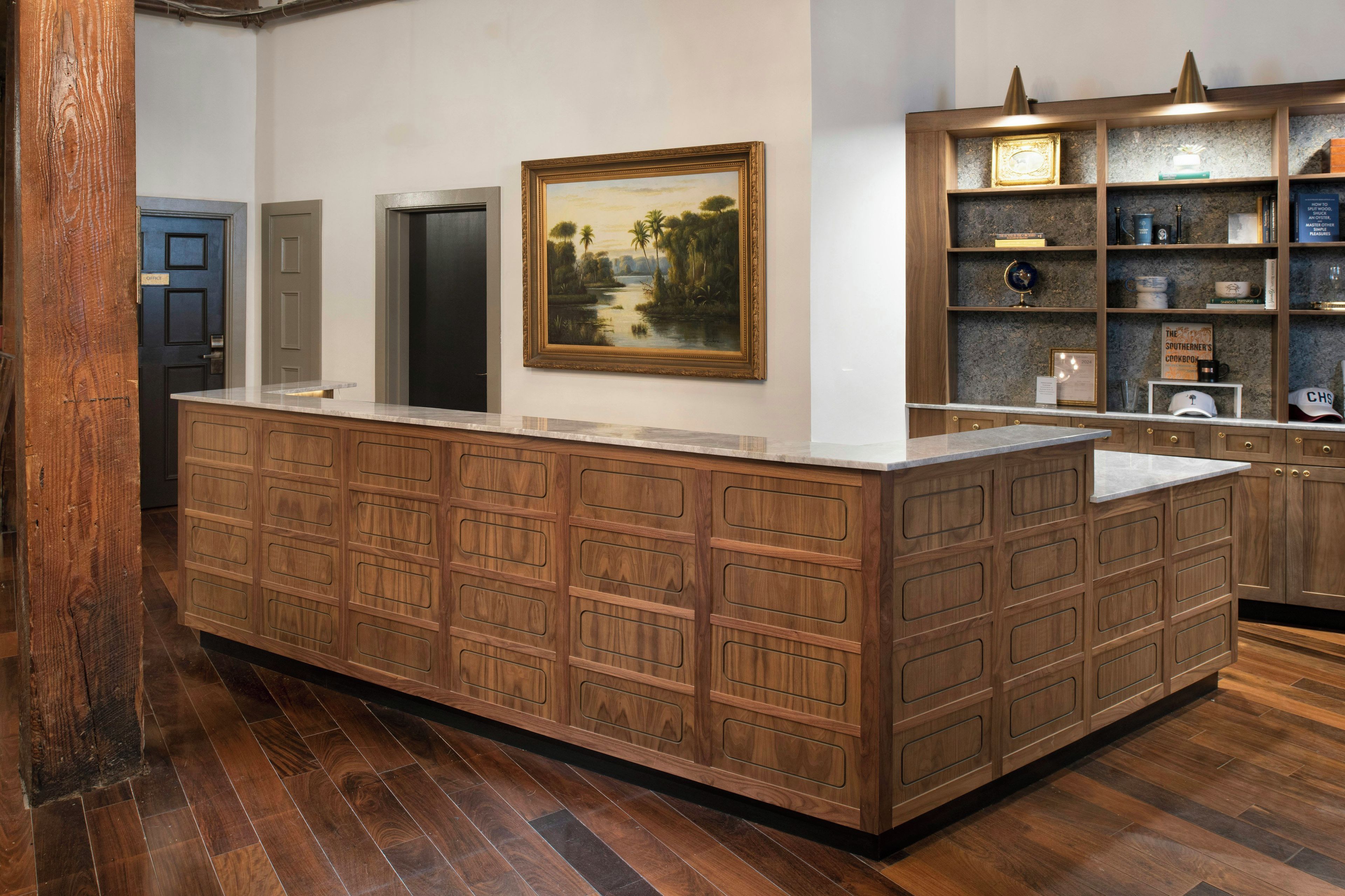 Une cuisine avec un îlot central en bois, un tableau accroché au mur et une étagère contenant divers objets.