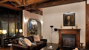 Una sala de estar acogedora con un sofá de cuero, una chimenea y un retrato en la pared.