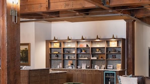 Amplia sala de estar con techo alto, vigas de madera, chimenea central y una zona de estar acogedora que incluye un sofá y sillones.