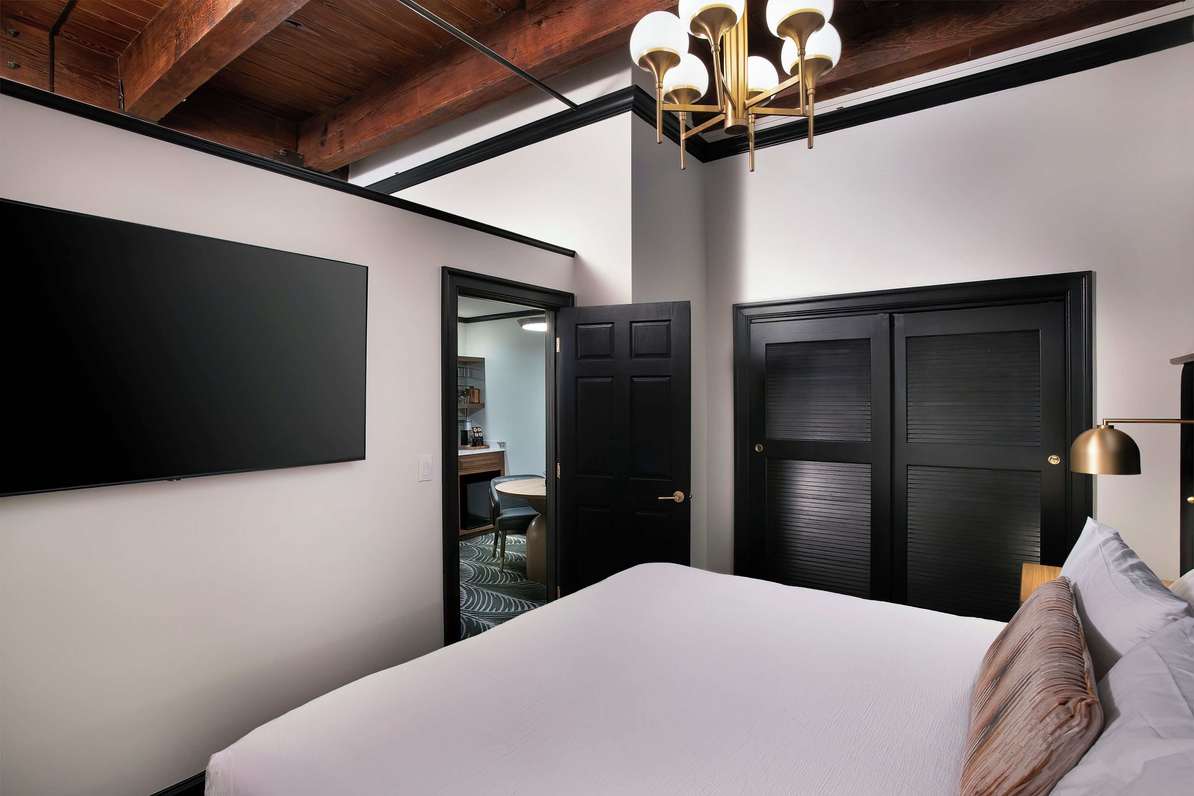 Une chambre dotée d’un grand lit, d’un téléviseur à écran plat fixé au mur et d’un luminaire au plafond.
