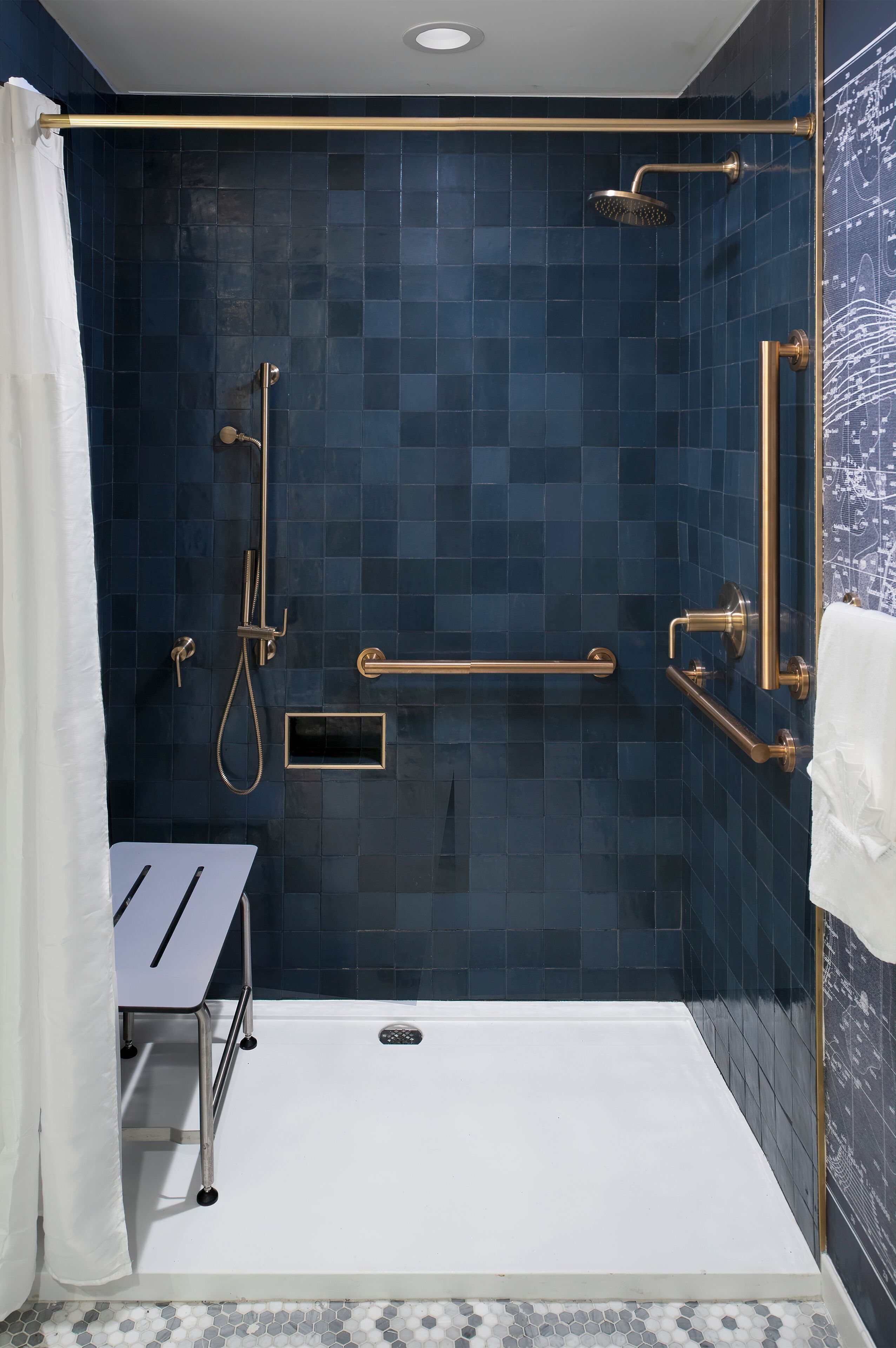 Un espace douche moderne avec des murs recouverts de carreaux bleus, une baignoire blanche et une serviette blanche.