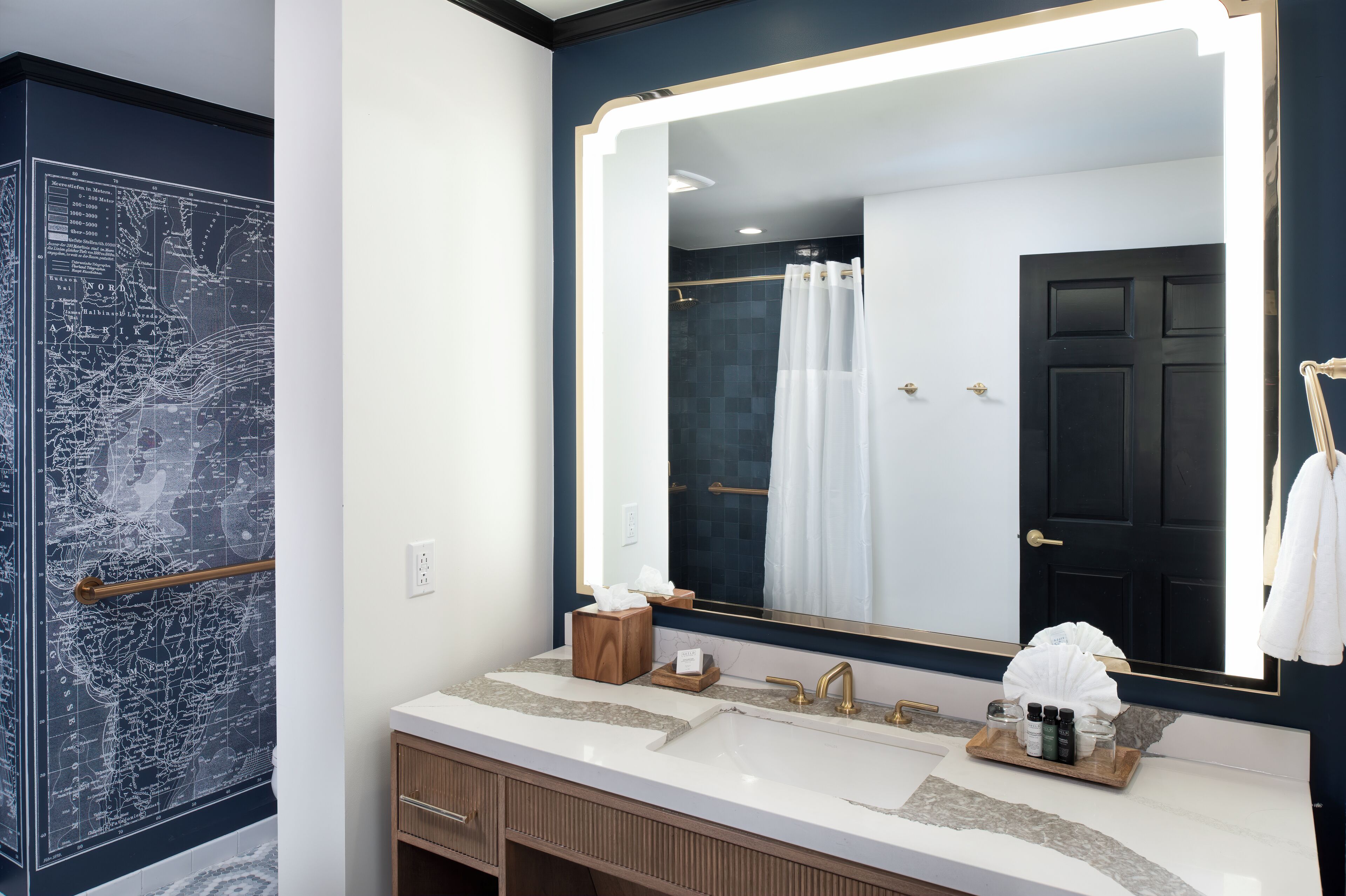 A bathroom with a large mirror, two sinks, a towel rack, and a map on the wall.