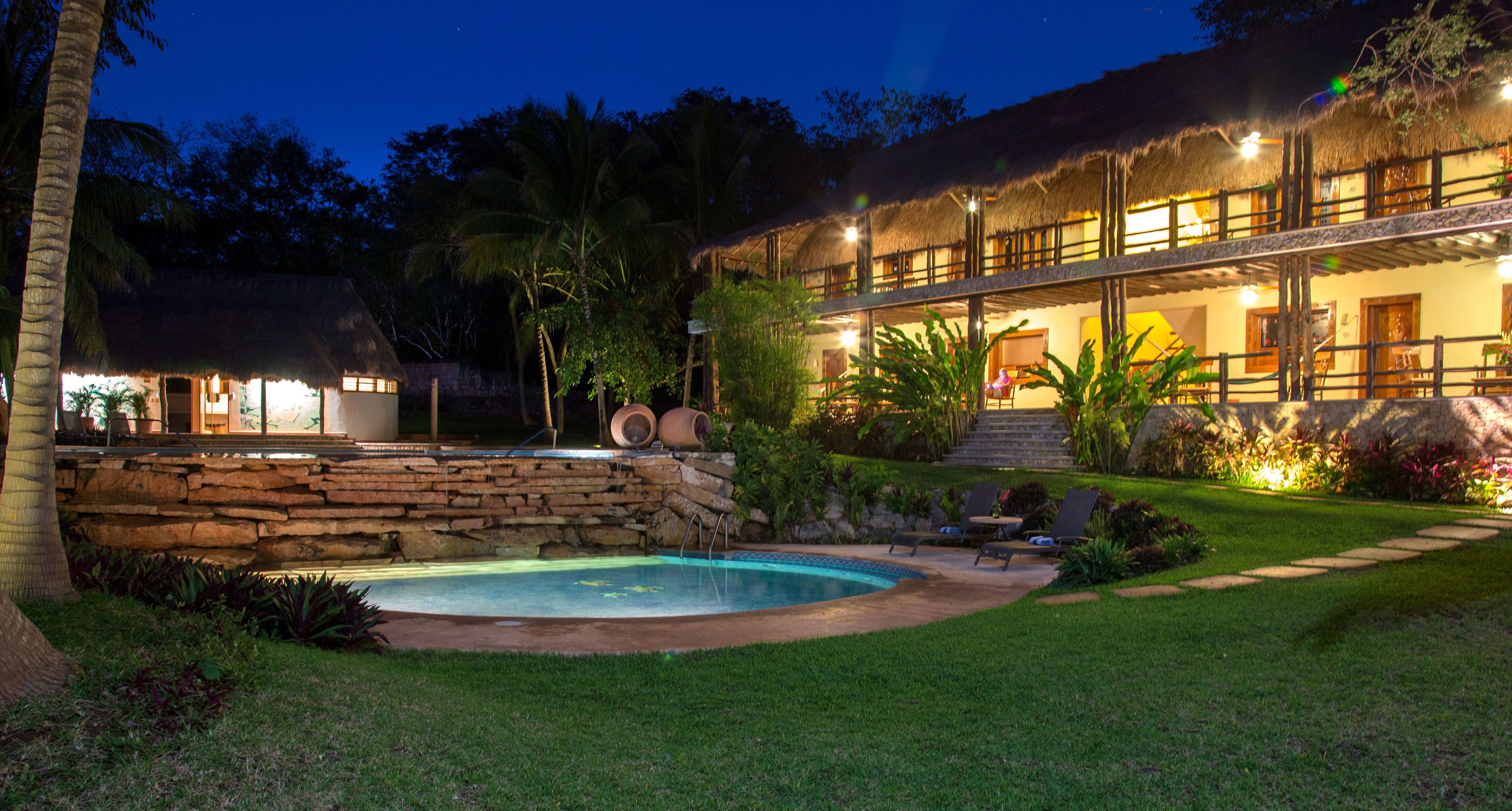 A resort with a pool, stone walls, and a thatched-roof building.