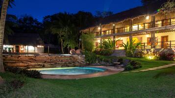 A resort with a pool, stone walls, and a thatched-roof building.