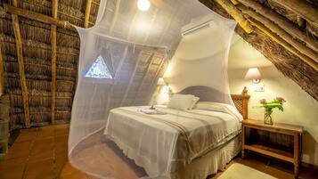 Un dormitorio acogedor con cama, mesita de noche, lámpara y ventana con vistas al exterior.