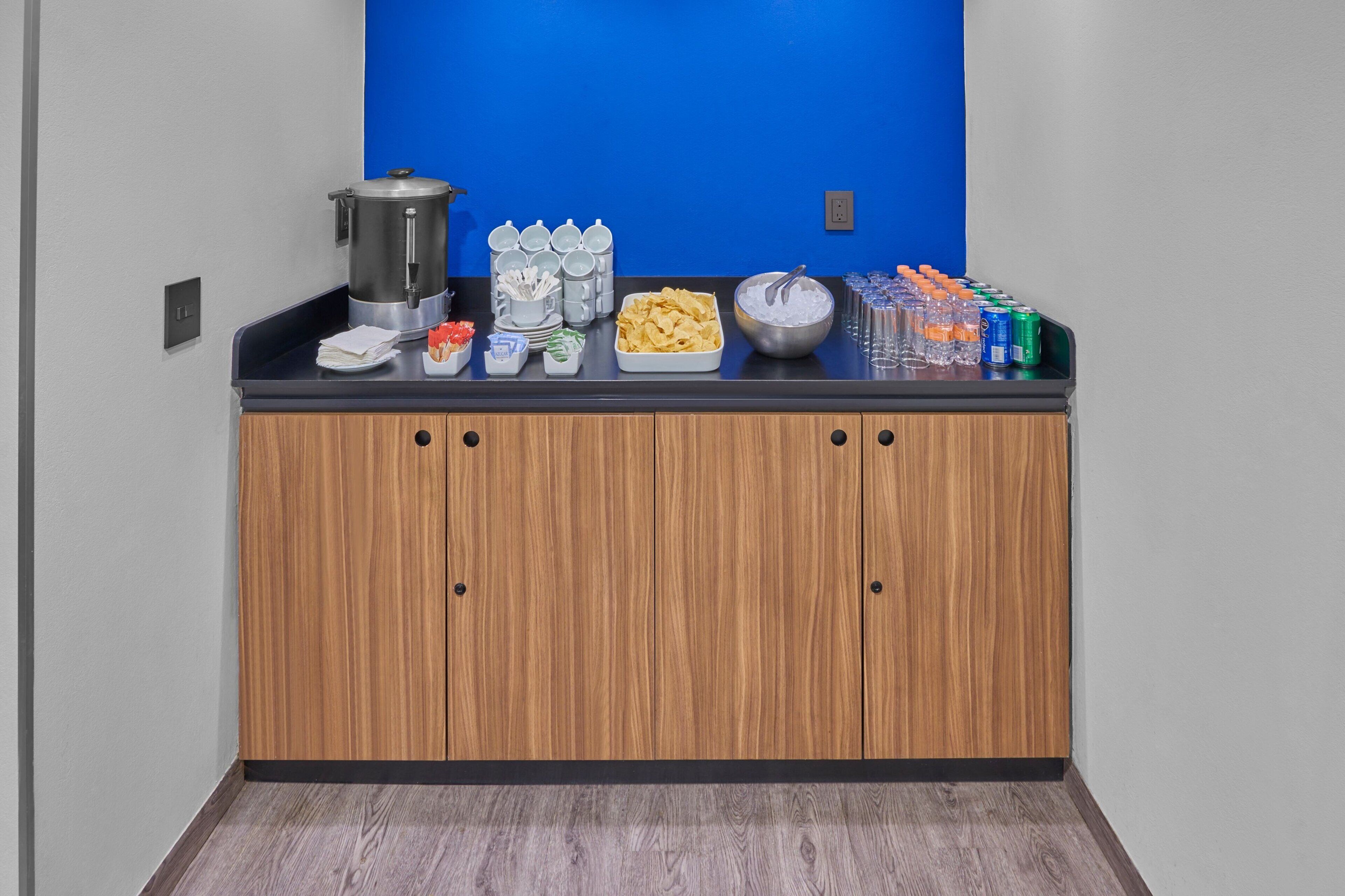 A buffet setup with a coffee station, snacks, and beverages.