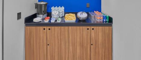 A buffet setup with a coffee station, snacks, and beverages.