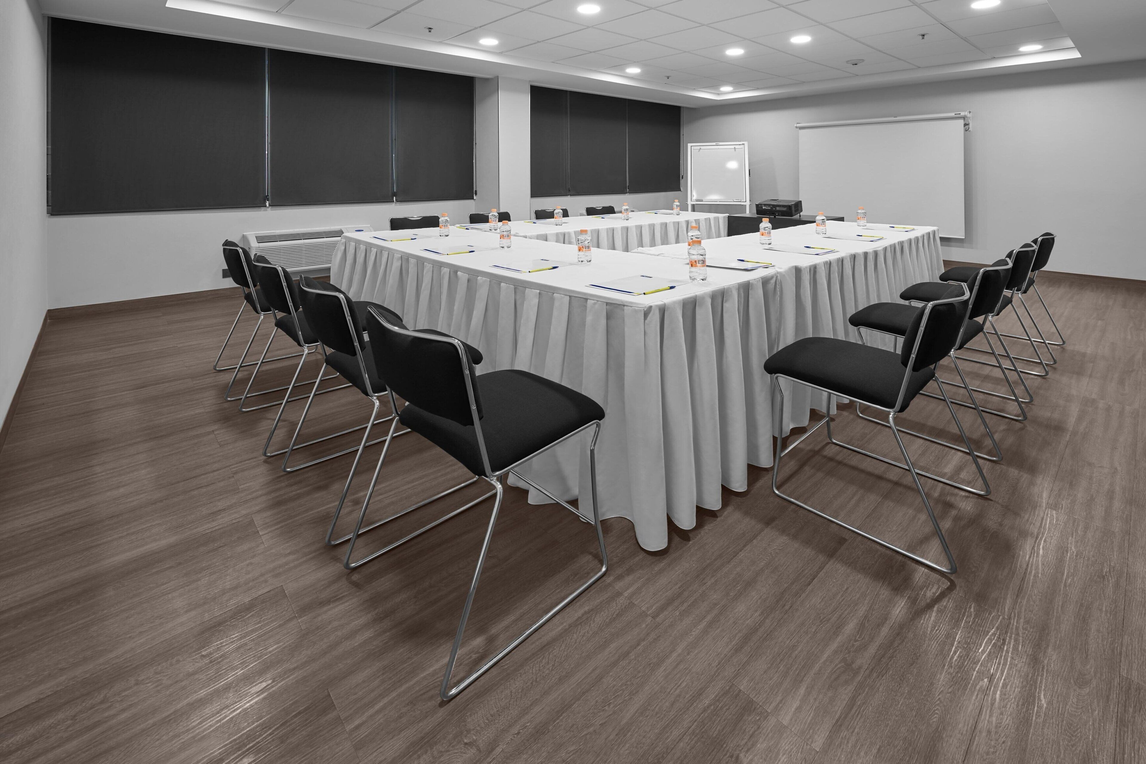 A conference room with a long table, black chairs, and a whiteboard.