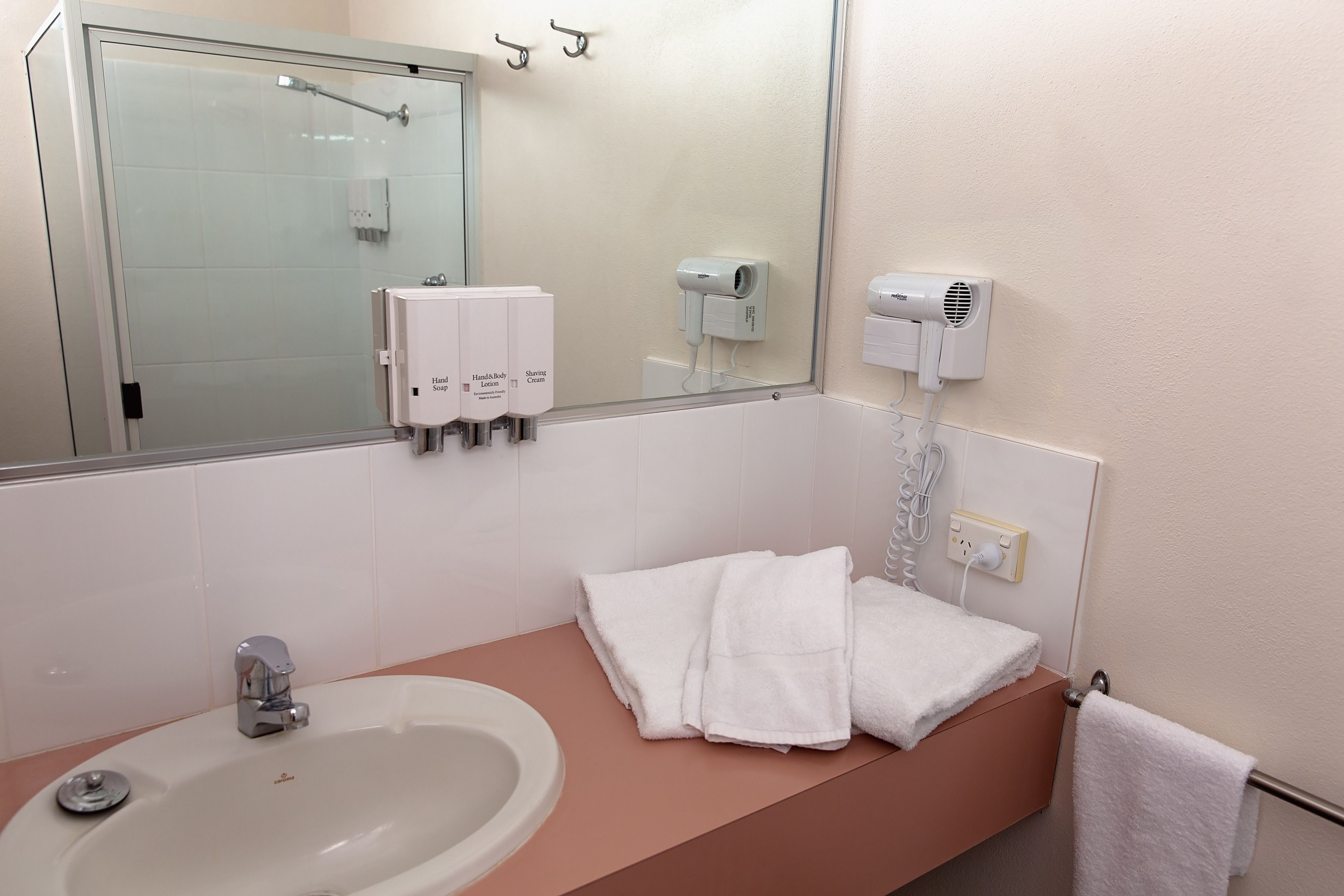 A bathroom with a sink, mirror, towel rack, and hairdryer.