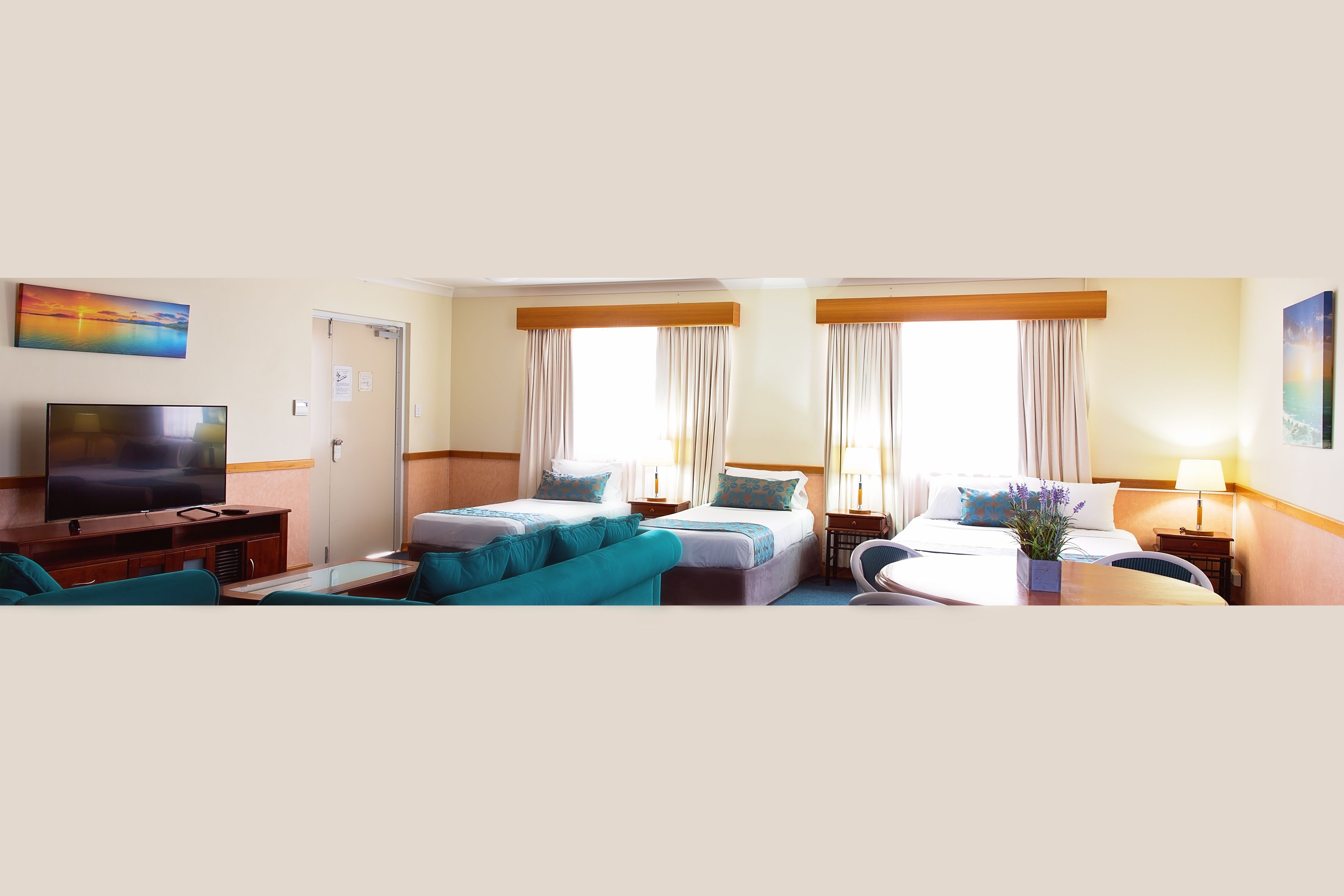 Habitación de hotel con dos camas, un televisor, un sofá y una mesita.