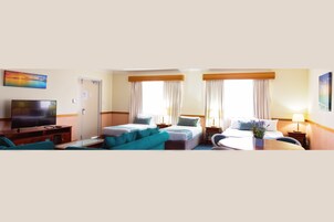Habitación de hotel con dos camas, un televisor, un sofá y una mesita.