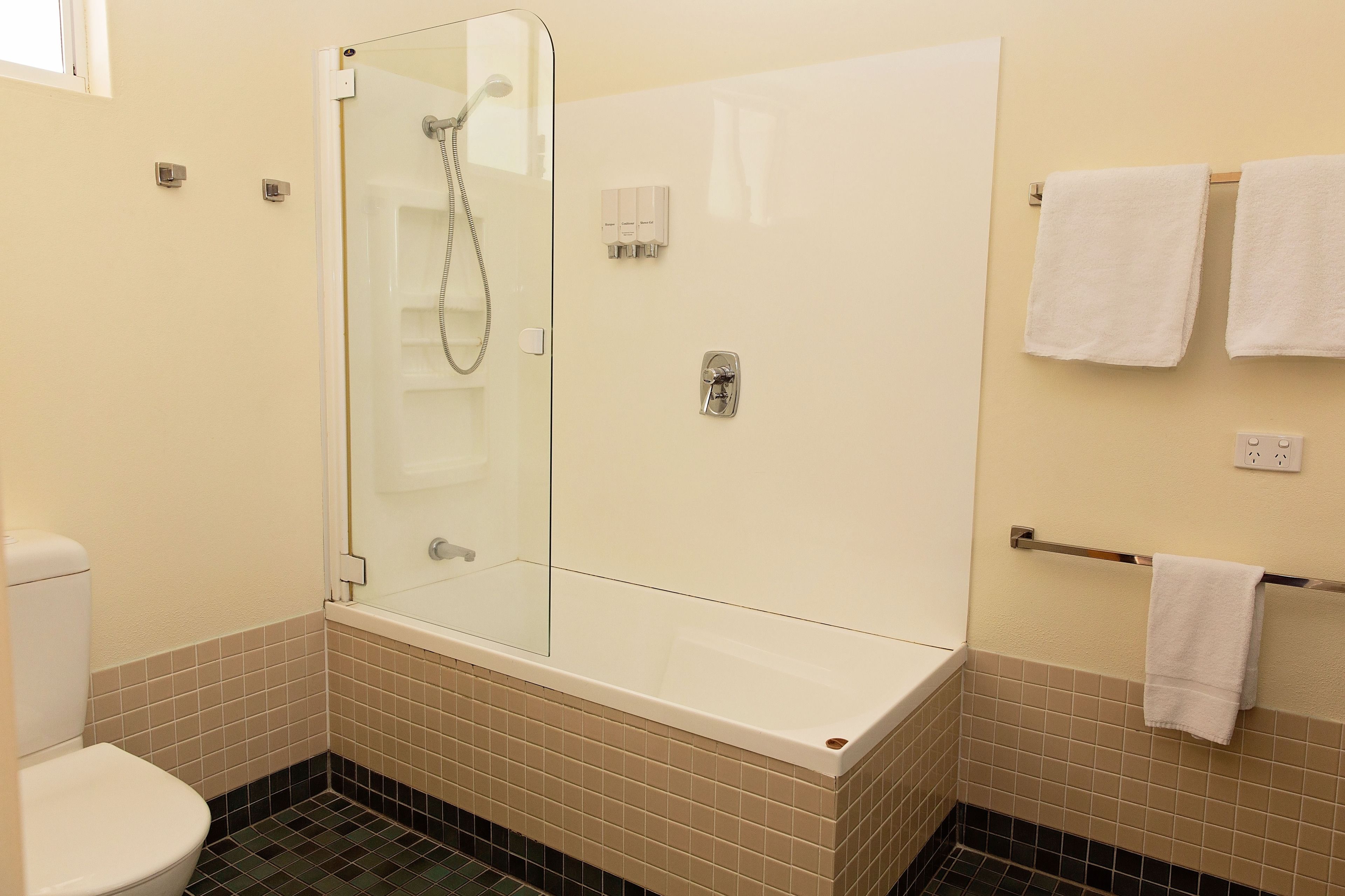 A bathroom with a glass-enclosed shower, a white bathtub, and a toilet.