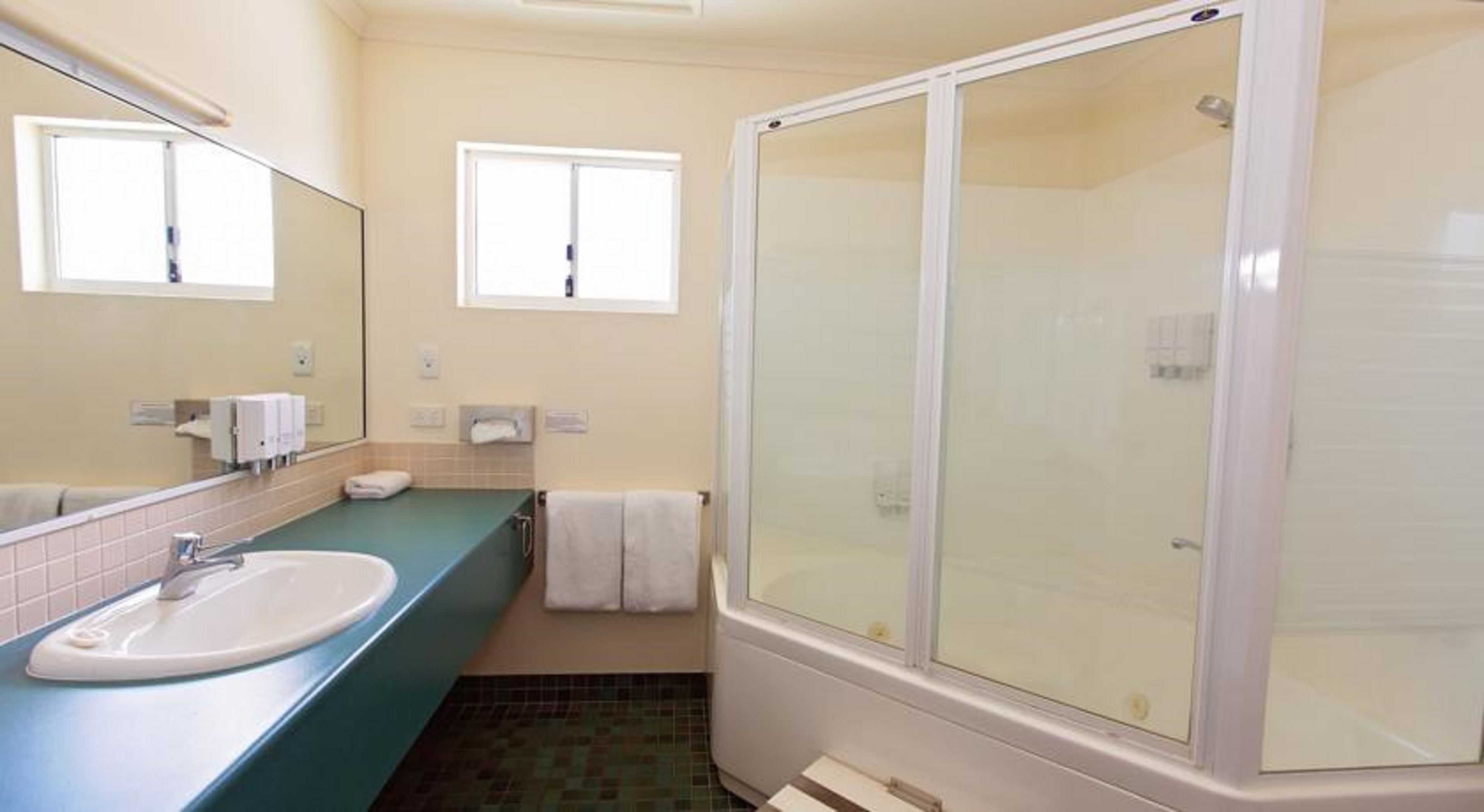 A bathroom with a sink, mirror, towel rack, and a glass-enclosed shower.