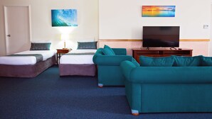 A hotel room with two beds, a sofa, a TV, and artwork on the walls. - White Lace Motor Inn (West Mackay)