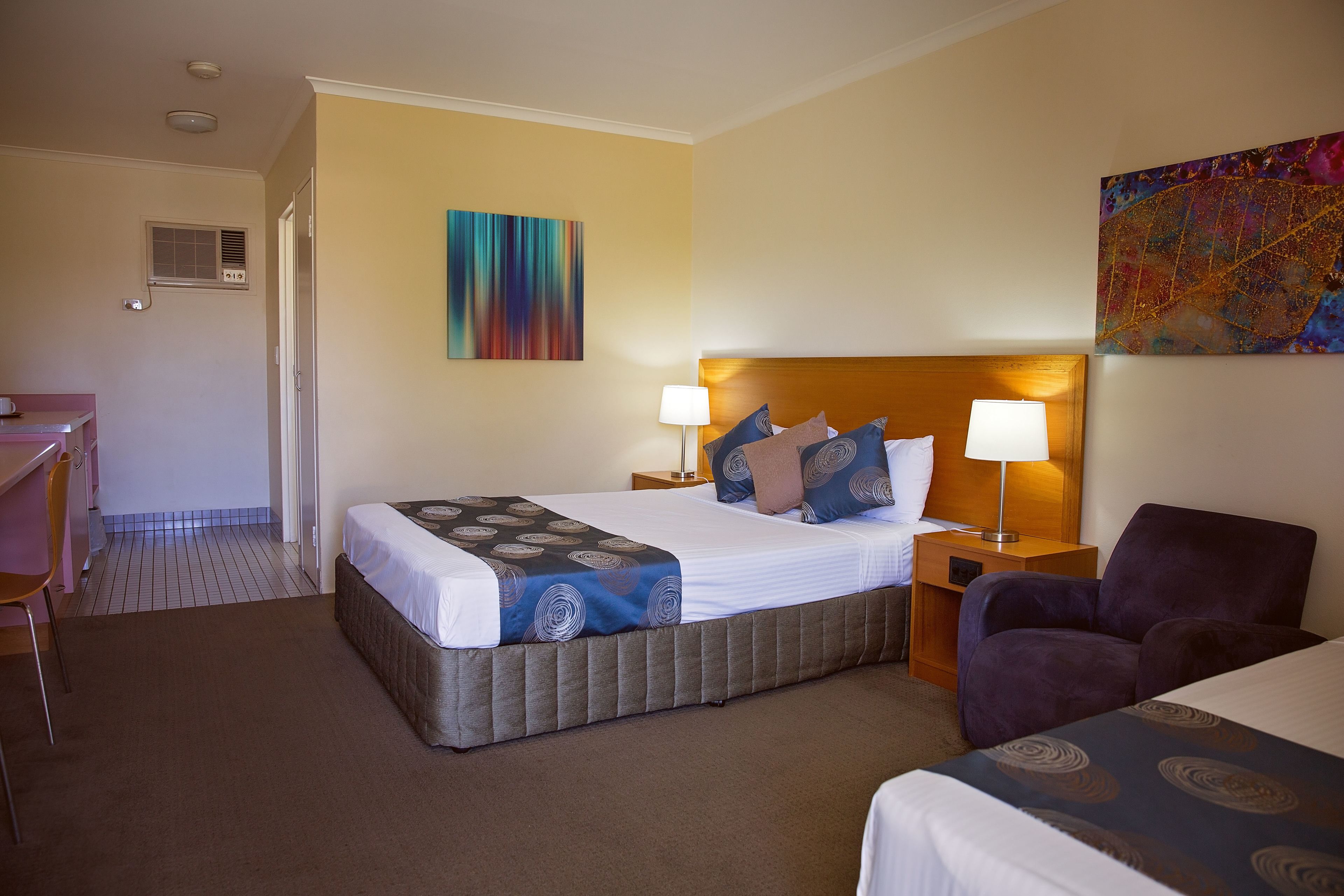 A hotel room with a bed, two bedside tables, a chair, a desk, and a small window.