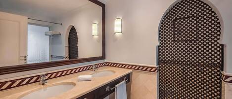 A bathroom with two sinks, a large mirror, and a decorative door.