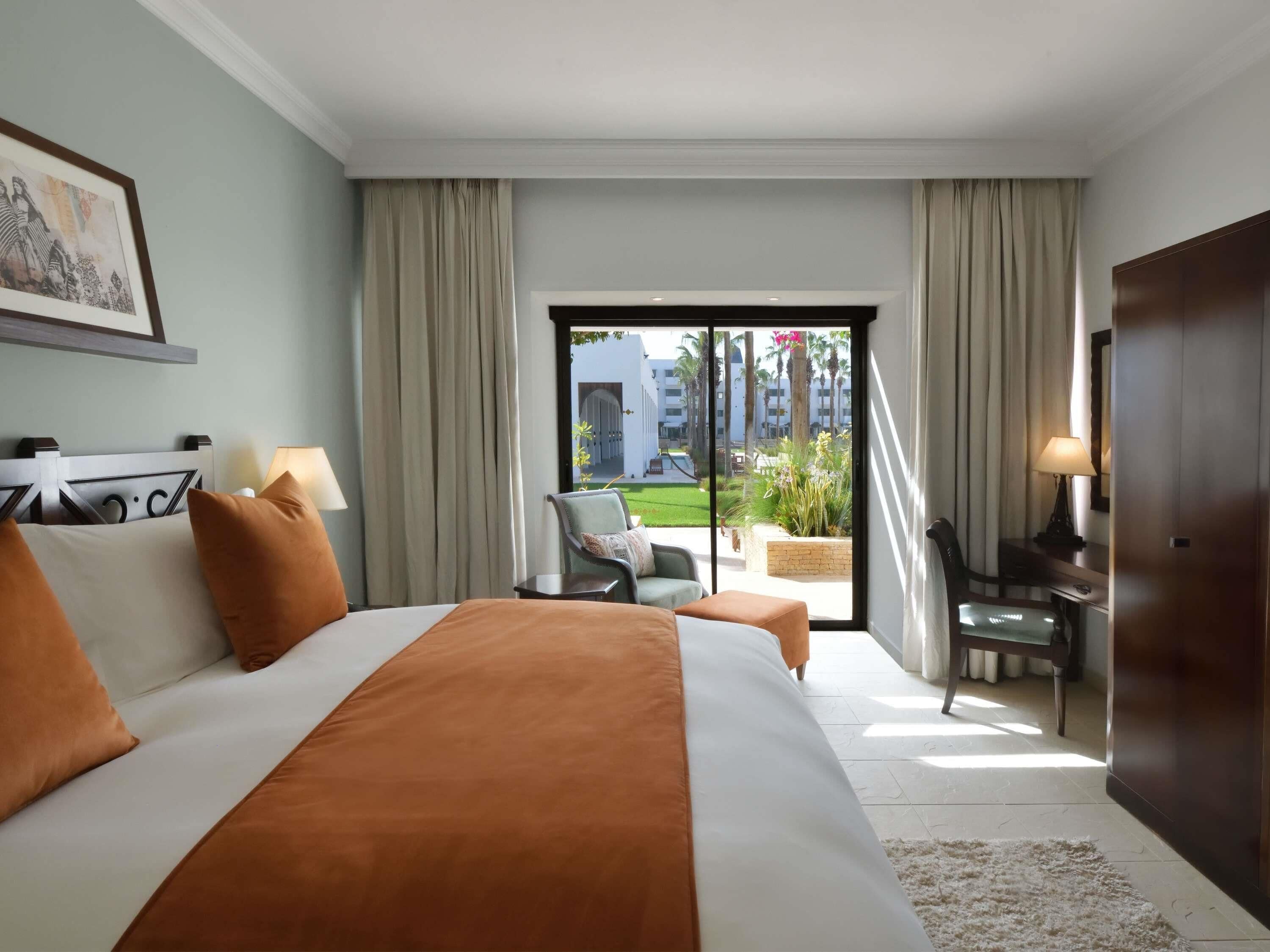 Habitación de hotel con una cama grande, un escritorio, una silla y vistas al exterior.