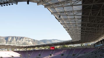 Un estadio con asientos escalonados, un marcador digital grande y un telón de fondo montañoso.