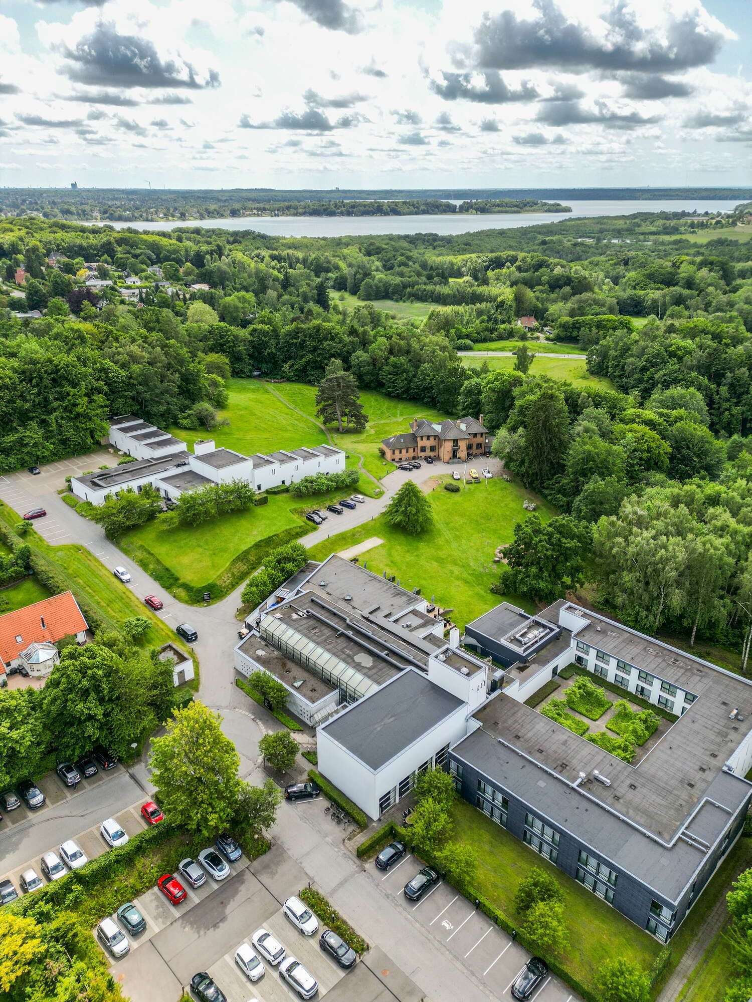 Vista aérea de un campus con varios edificios, zonas de estacionamiento y espacios verdes.