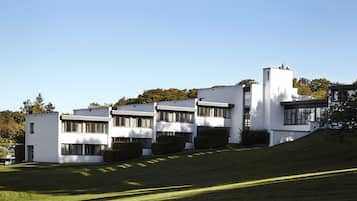 Un edificio moderno con techo plano, ventanas grandes y un césped cuidado.