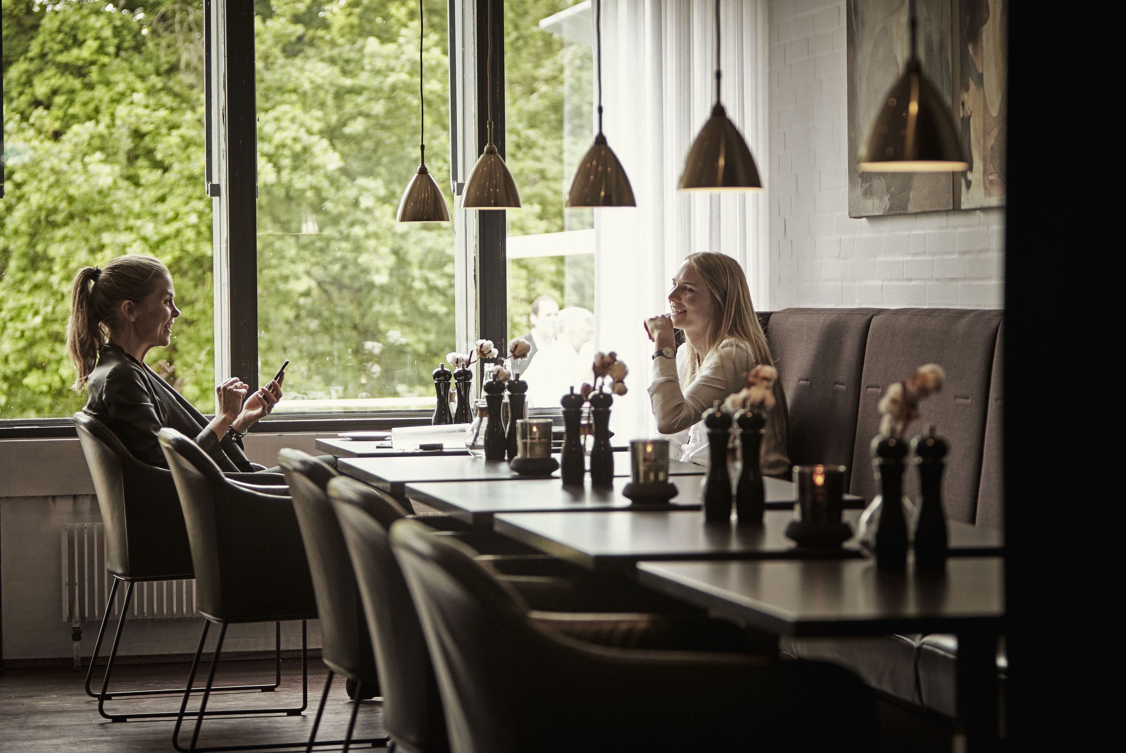 Een moderne eethoek met een lange tafel, zwarte stoelen en hangende吊灯.