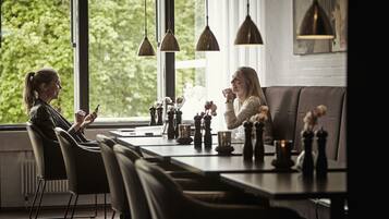 Een moderne eethoek met een lange tafel, zwarte stoelen en hangende吊灯.